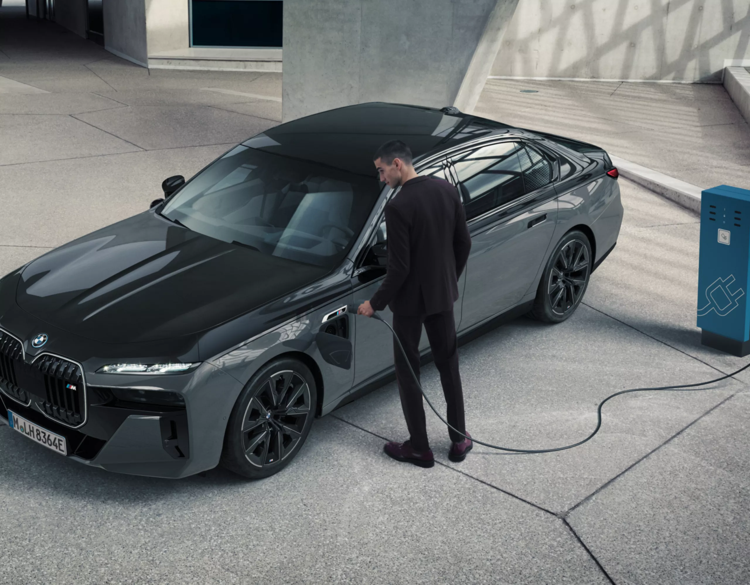 Siyah bir BMW, parlak beton ve cam bir odada şarj oluyor