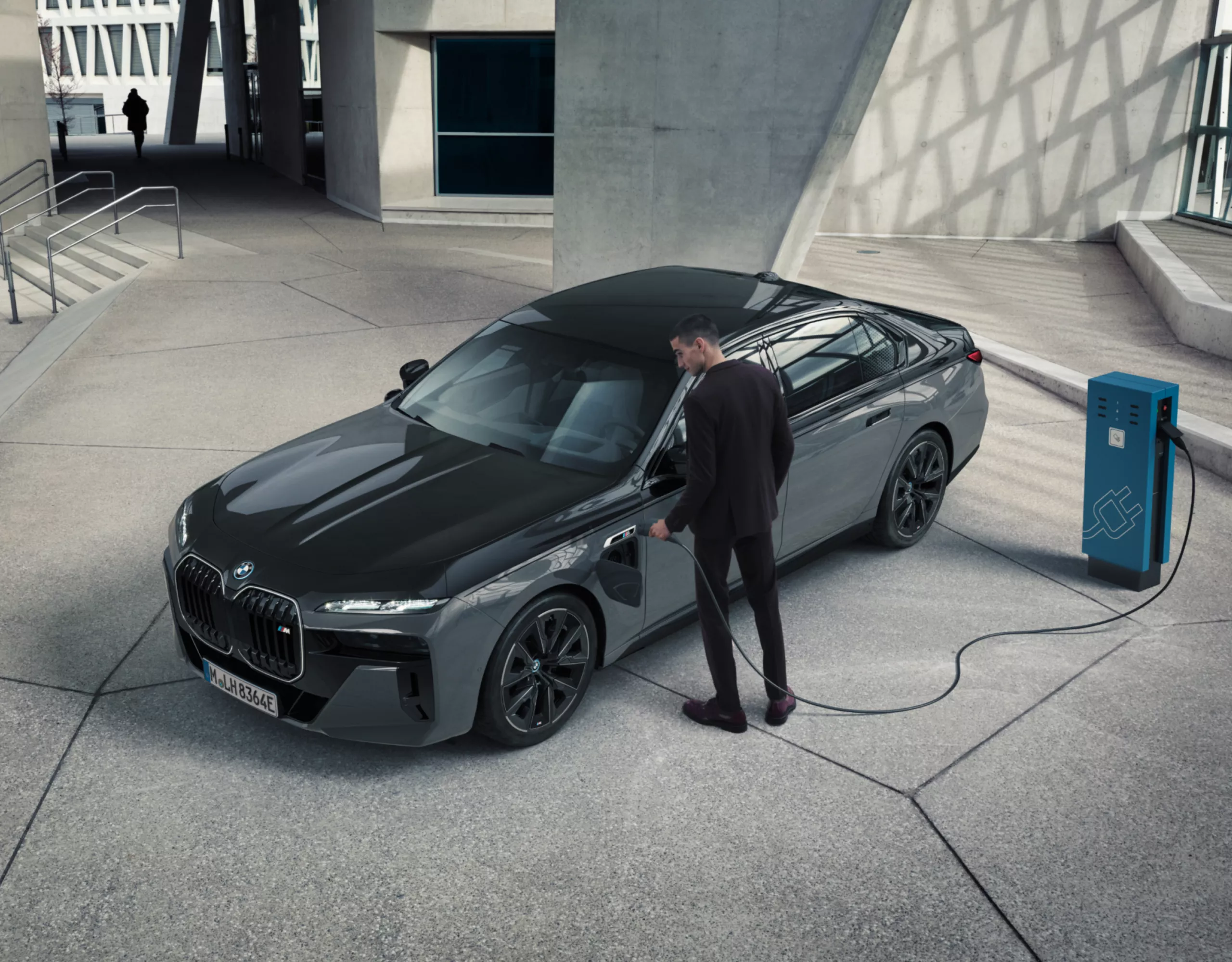 A black BMW charges in a bright concrete and glass room