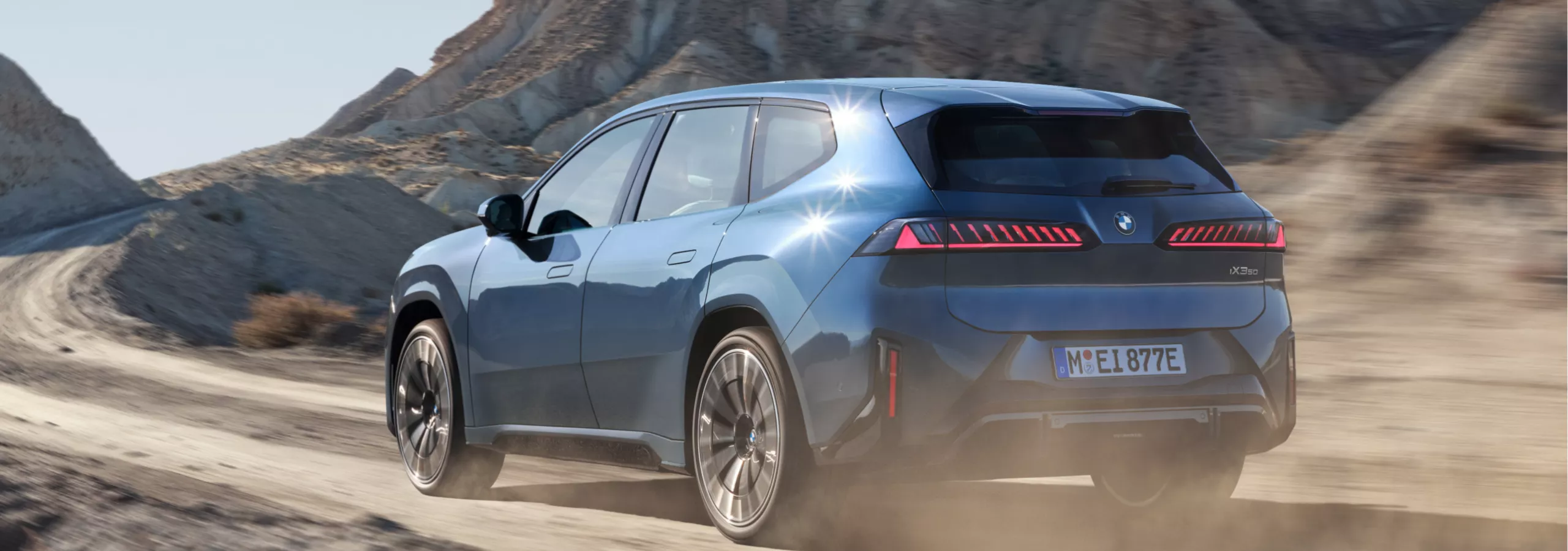 Ein BMW iX3 fährt über eine Geröllstraße durch ein Felsengebirge